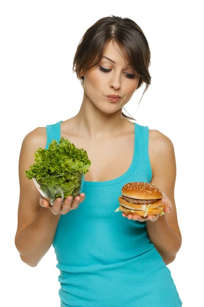 Женщина, делая решение между здоровый салат и фаст-фуд — стоковое фото