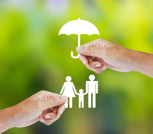Рукой придерживая бумагу семьи и зонтик на зеленом фоне, страхования понятие — стоковое фото