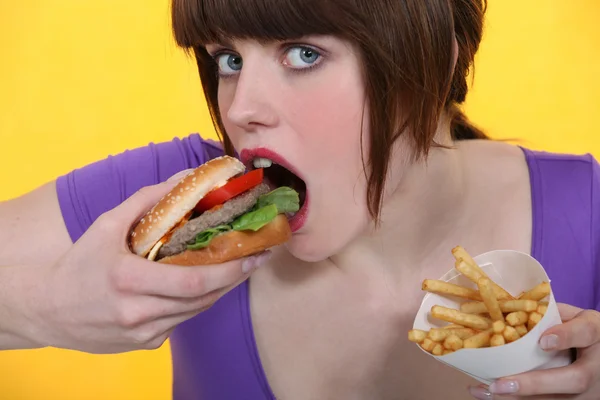 Женщина ест гамбургер и картофель фри — стоковое фото