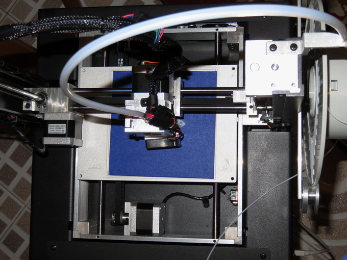 Принтер Inno3D Printer D1 отличается открытой конструкцией (вид сверху). Слева расположена катушка с PLA-нитью, которая по рукаву подается на экструдер 